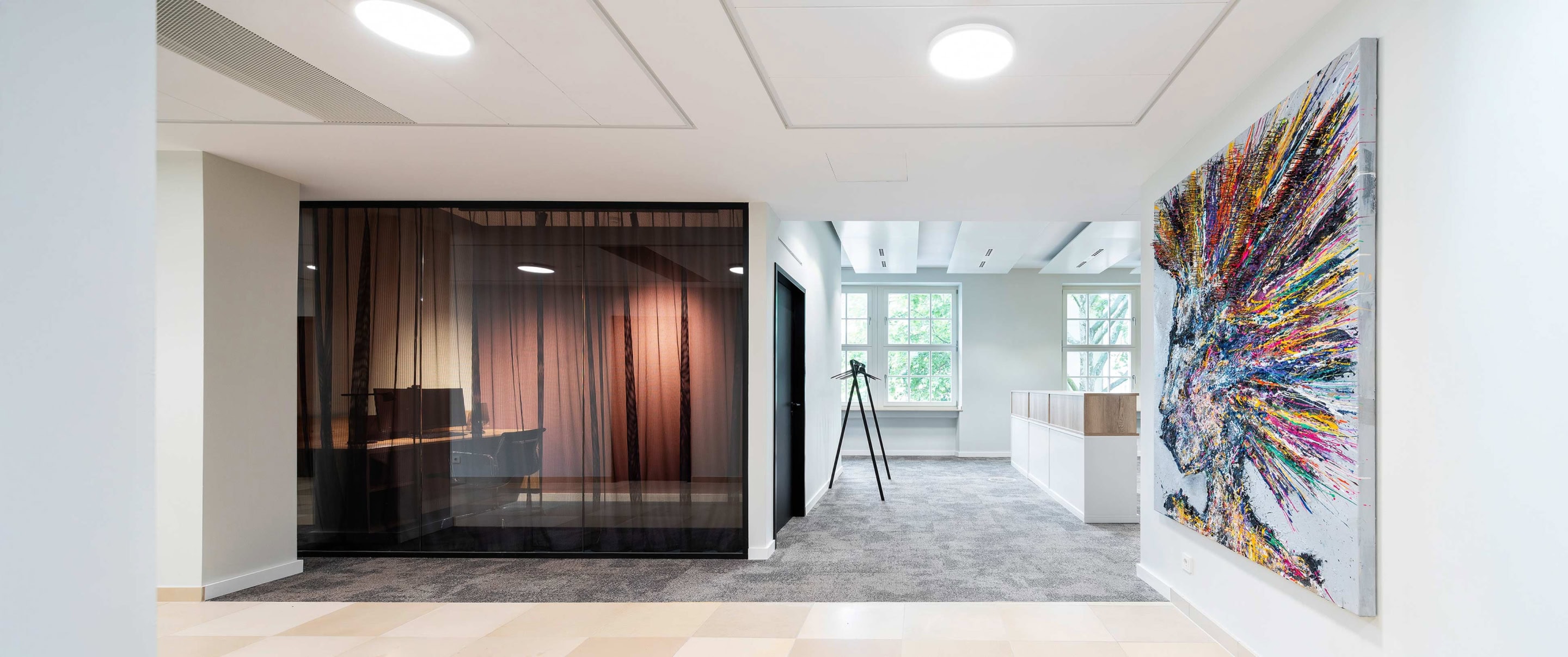 Besprechungsraum der Sozietät Ganteführer mit Bild an der Wand und Blick auf ein Office hinter Vorhängen